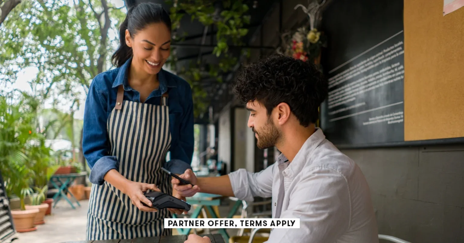 SOCIAL IMAGE PARTNER OFFER TERMS APPLY Man making a contacless payment at a restaurant using his cel.webp