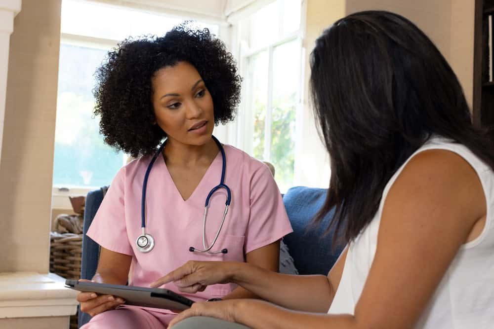 Nurse with curly hair showing tablet patient home 1.jpg